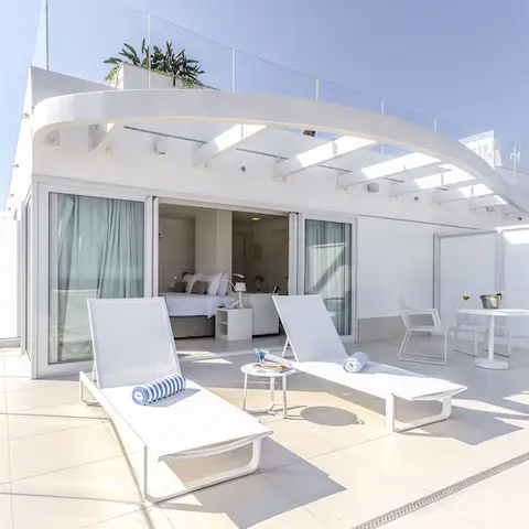 Suíte com terraço privativo, espreguiçadeiras e mesa ao ar livre.