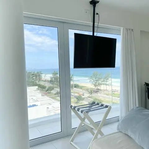 Quarto com janela do chão ao teto e vista para a praia.